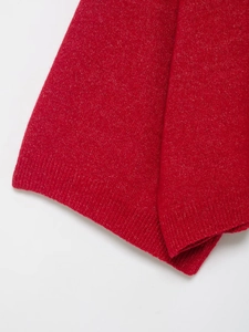 Macro shot of red knit sweater with subtle metallic glitter yarn and ribbed cuff detail