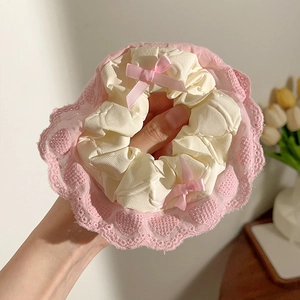 Detailopname van een roze kanten scrunchie met zijden linten en verfijnde texturen