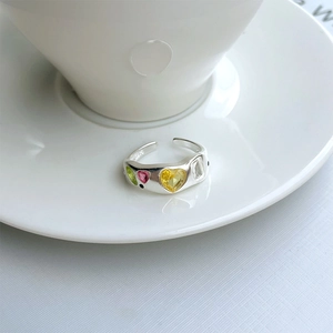 Detail of S925 sterling silver ring with colorful heart gemstones on white ceramic
