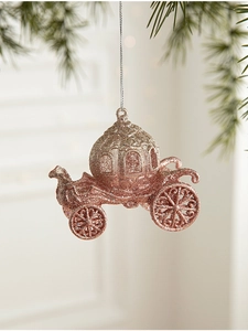 Close-up of rose gold pumpkin carriage Christmas ornament with glitter finish on pine branch