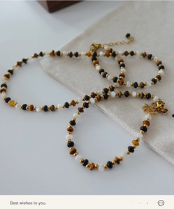 Close-up of tiger eye and black agate beaded necklace and bracelet set with gold accents