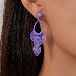 Close-up of matte purple drop earrings with hollow leaf tassels on a model's ear