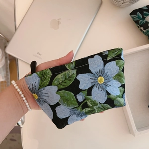 Handheld jacquard mini pouch with light blue floral pattern and smooth top zipper closure