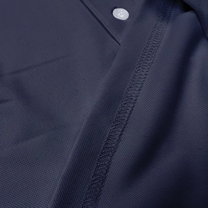 Macro shot of dark blue breathable mesh polo fabric with button and stitching details