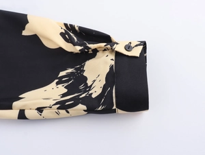 Close-up of buttoned cuff on long sleeve dress with abstract black and beige print