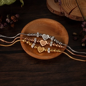 Detailed shot of three bead bracelets in silver gold and rose gold with heart charms