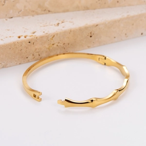 Minimalist wavy gold bamboo texture bangle bracelet with a secure buckle on white background