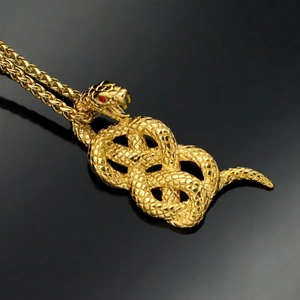 Golden stainless steel snake pendant with red gemstone eyes on a black background