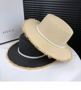 Close-up of woven straw hats featuring pearl bands and frayed edge details in beige and black