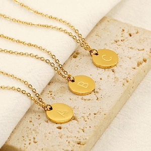 Polished gold circular alphabet pendants with A, B, and C engravings on stone base