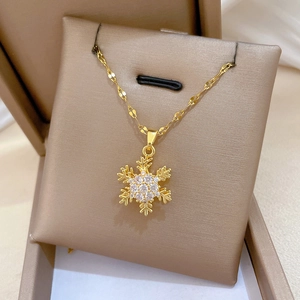 Detail of a rotating snowflake pendant with white zircons and a gold water wave chain