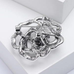 Macro shot of silver filigree spider lily brooch with textured hollow design and pin detail