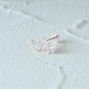 Macro shot of a silver s925 crown labret stud with sparkling gemstones on stone surface