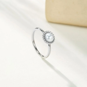 Close-up of minimalist silver stainless steel ring featuring a round white pearl