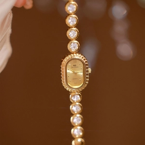 Close-up of a gold oval watch with crystal encrusted band and elegant quartz dial