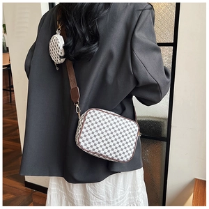 Detail view of stylish crossbody camera bag with geometric pattern and round coin pouch