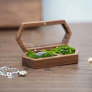 Detail of hexagonal walnut wood ring box with transparent window and moss padding