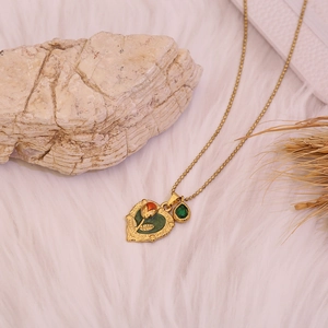 Collier cœur doré élégant avec motif rose et pierre verte sur fond de fourrure blanche
