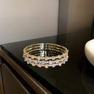 Detailed close-up of a three-row gold bracelet featuring pave-set square crystals and reflections