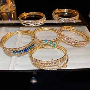 Detail of layered gold zircon bracelets with multicolor gemstones on display stand