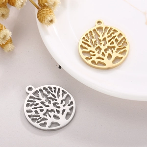 Golden and silver stainless steel Tree of Life hollow pendants on a ceramic plate