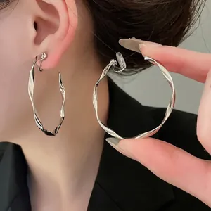 Minimalist twisted silver metal hoop earrings with comfortable clip-on silicone pads