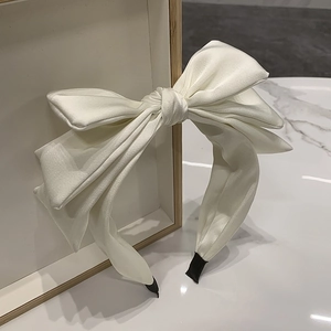Detail of white satin triple-layered bow headband with elegant glossy silk texture