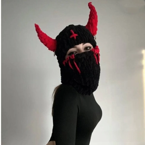 Detail of knitted black balaclava with red devil horns and cross stitching