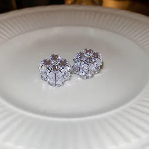 Minimalist cubic zircon square stud earrings on a textured ceramic dish in warm lighting