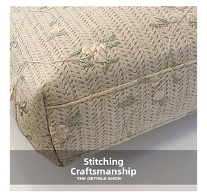 Détail de couture sur sac fourre-tout en paille beige avec broderie florale en dentelle