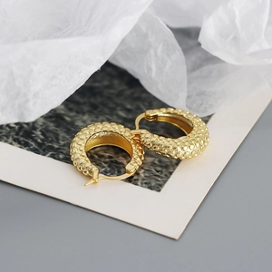 Close-up of S925 sterling silver stamp on golden hoop earrings with textured finish
