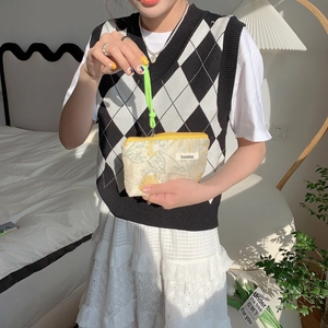 Close-up of floral embroidery cosmetics bag with green handle and yellow zipper detail