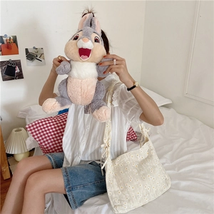 Detail of a white canvas tote bag with yellow daisy prints and a rabbit plush toy