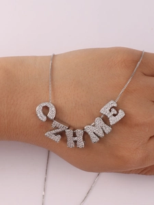 Detailed view of a silver necklace with sparkling zircon-studded ZHME letter pendants
