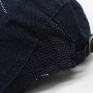Detail of navy mesh beret showing breathable fabric, precision stitching and metal buckle