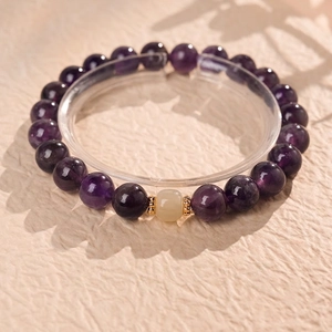Elegant amethyst and Hetian jade bracelet with golden spacers on a textured beige backdrop
