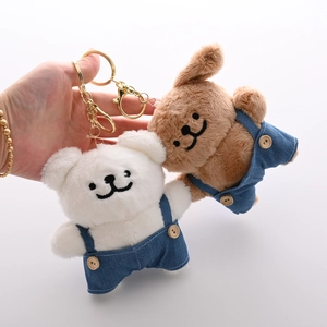 Cute plush puppy keychains in white and brown wearing blue denim overalls with gold hooks