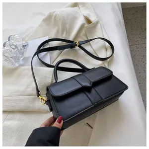 Vue détaillée du sac bandoulière en cuir noir mat avec accessoires dorés sur une veste chic