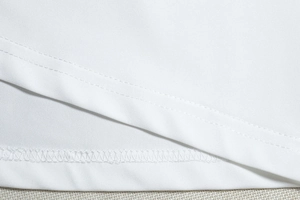 Close-up of double-needle stitching and hem detail on a white sleeveless dress