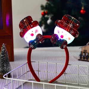 Detail of luminous Christmas headband with glowing snowman and plaid hats in gift basket