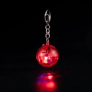 Macro shot of red glowing disco ball keychain with LED light reflection on black background