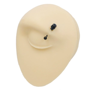 Macro shot of black skull eyebrow ring on a silicone model for piercing display