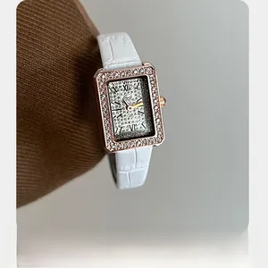 Dettaglio macro dell'orologio Gedi quadrato con lunetta di cristalli e cinturino bianco