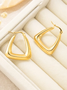 Detailed close-up of 18K gold-plated geometric hoop earrings on a velvet jewelry box