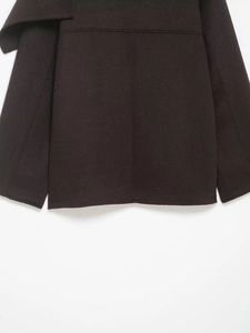 Detailed view of dark wool blend fabric texture and stitching on the jacket hem