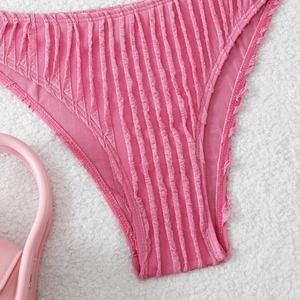 Pink textured bikini bottoms with vertical pleats on a soft white plush background