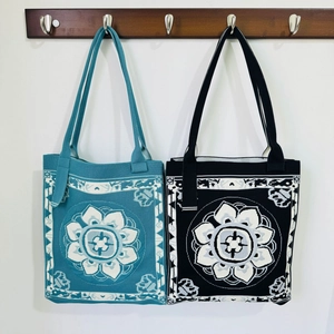 Knitted tote bags with floral patterns in blue and black colors hanging on a wooden rack