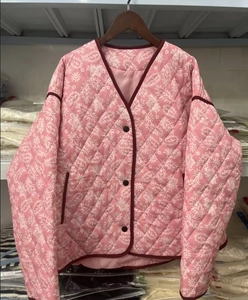 Detail of pink quilted jacket with white paisley patterns and single-breasted V-neck line