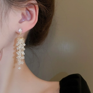 Détail de boucles d'oreilles pendantes dorées avec des perles en cristal sur un mannequin