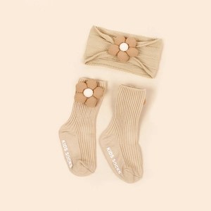 Détail de chaussettes en maille et bandeau pour bébé avec fleurs en peluche et antidérapant